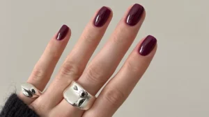 Burgundy nail designs on short oval nails with chunky silver rings